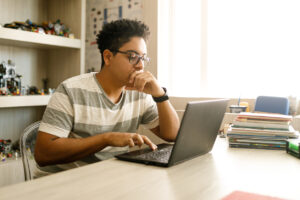 Adolescente que estuda com o notebook em casa.