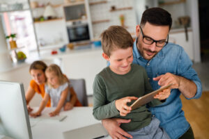 Pai auxiliando filho com tablet.