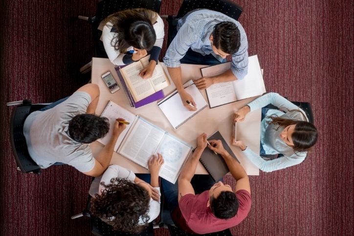 grupo de estudantes reunidos em círculo, discutindo e compartilhando planos de estudos.