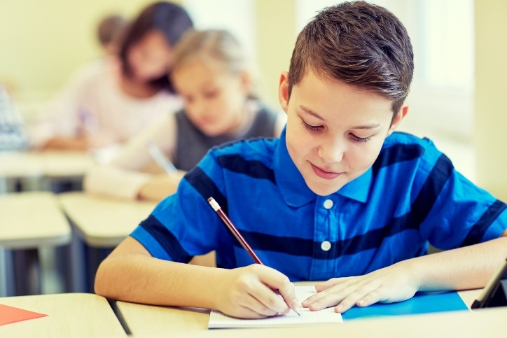 menino fazendo atividade avaliativa em sala de aula.